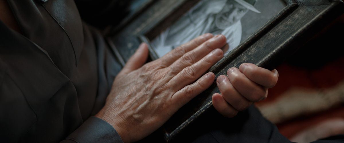 An elderly man holding hands with a family member