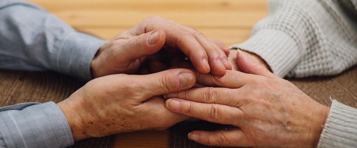 A family member holding an elderly person's hand in comfort