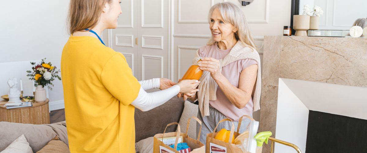 A caregiver helping an elderly woman at home during a day visit