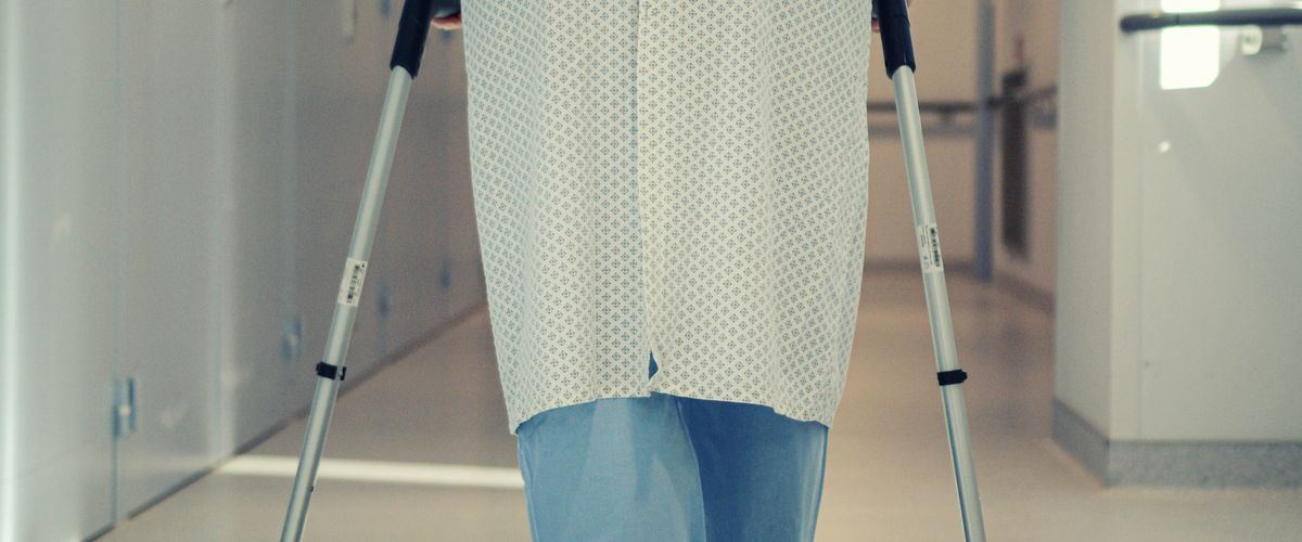 A recovering patient walking with support after a hospital stay