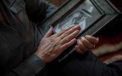 An elderly man holding hands with a family member