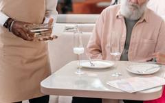 A caregiver serving a meal to an elderly man in his home