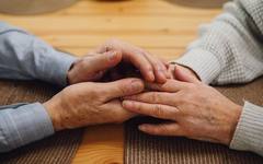 A family member holding an elderly person's hand in comfort