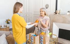 A caregiver helping an elderly woman at home during a day visit